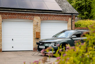 A car parked in front of a house with a solar panel on the roof