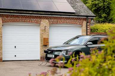 A car parked in front of a house with a solar panel on the roof