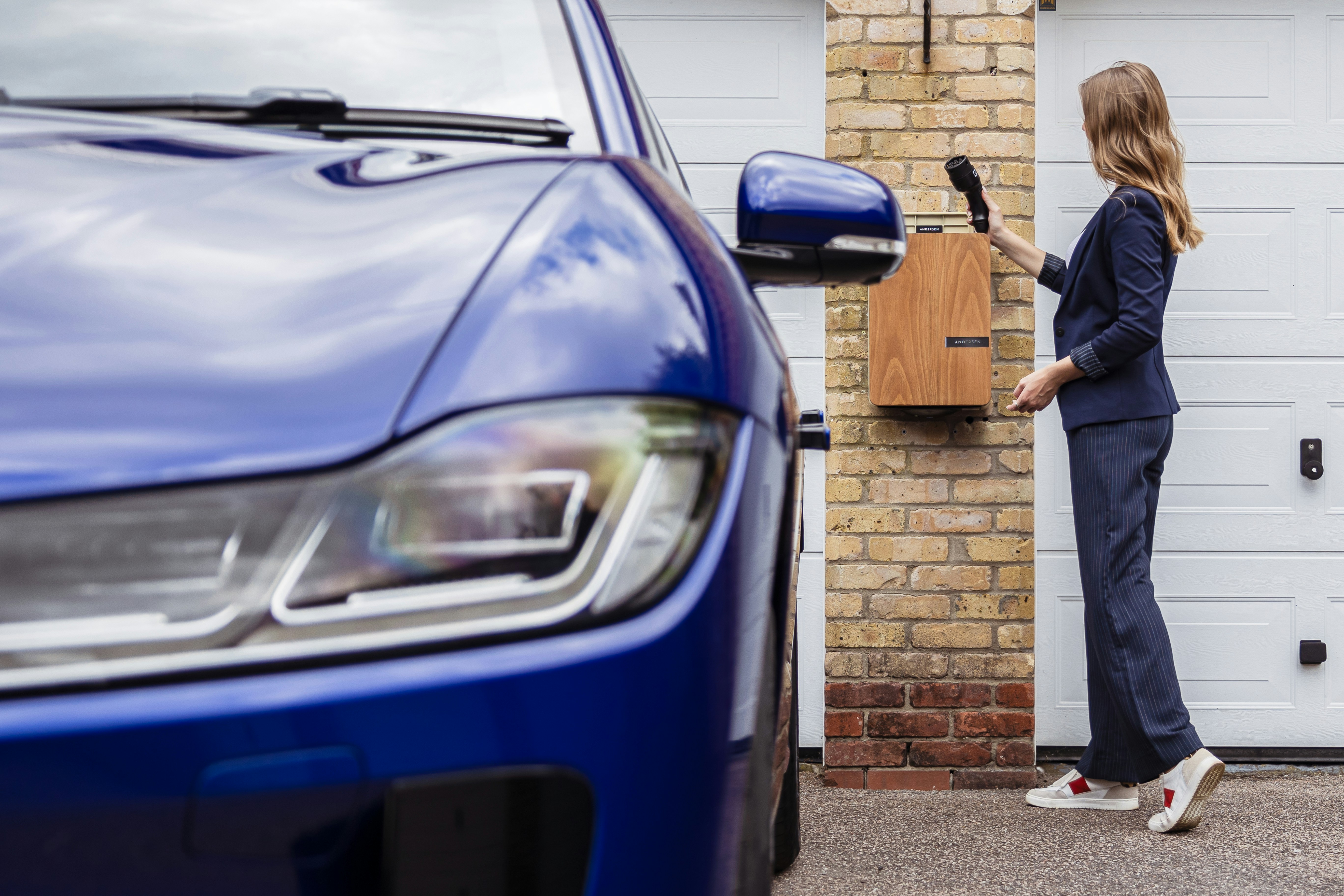 A woman standing in front of a blue car