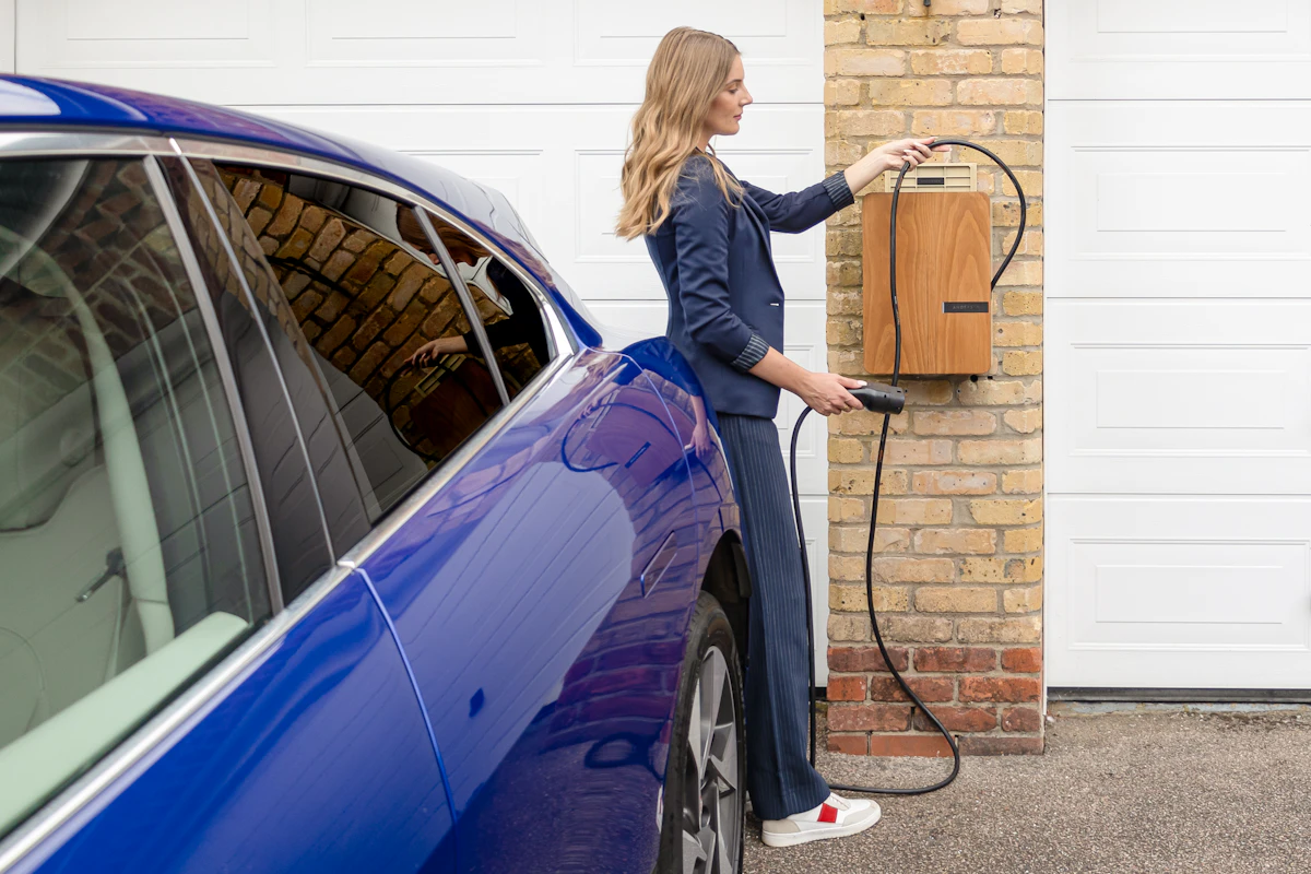 Femme rechargeant sa voiture électrique avec une borne murale à domicile