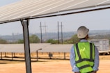 A man in a safety vest standing under a solar panel