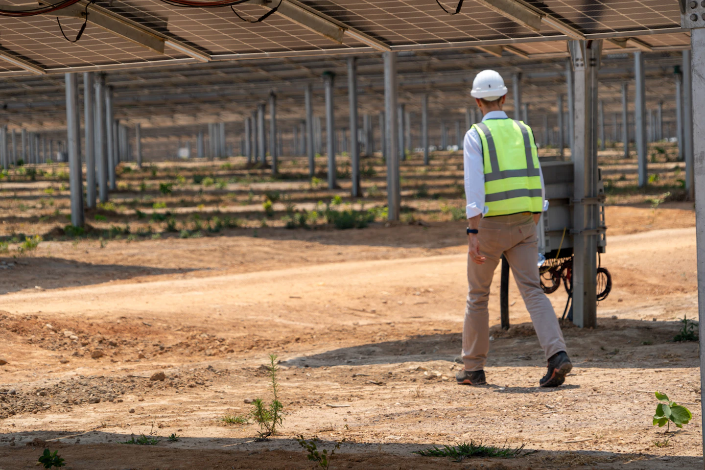 An engineer in a hard hat and safety vest inspecting a solar installation