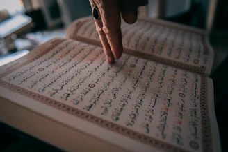 A person's hand on a book with writing on it