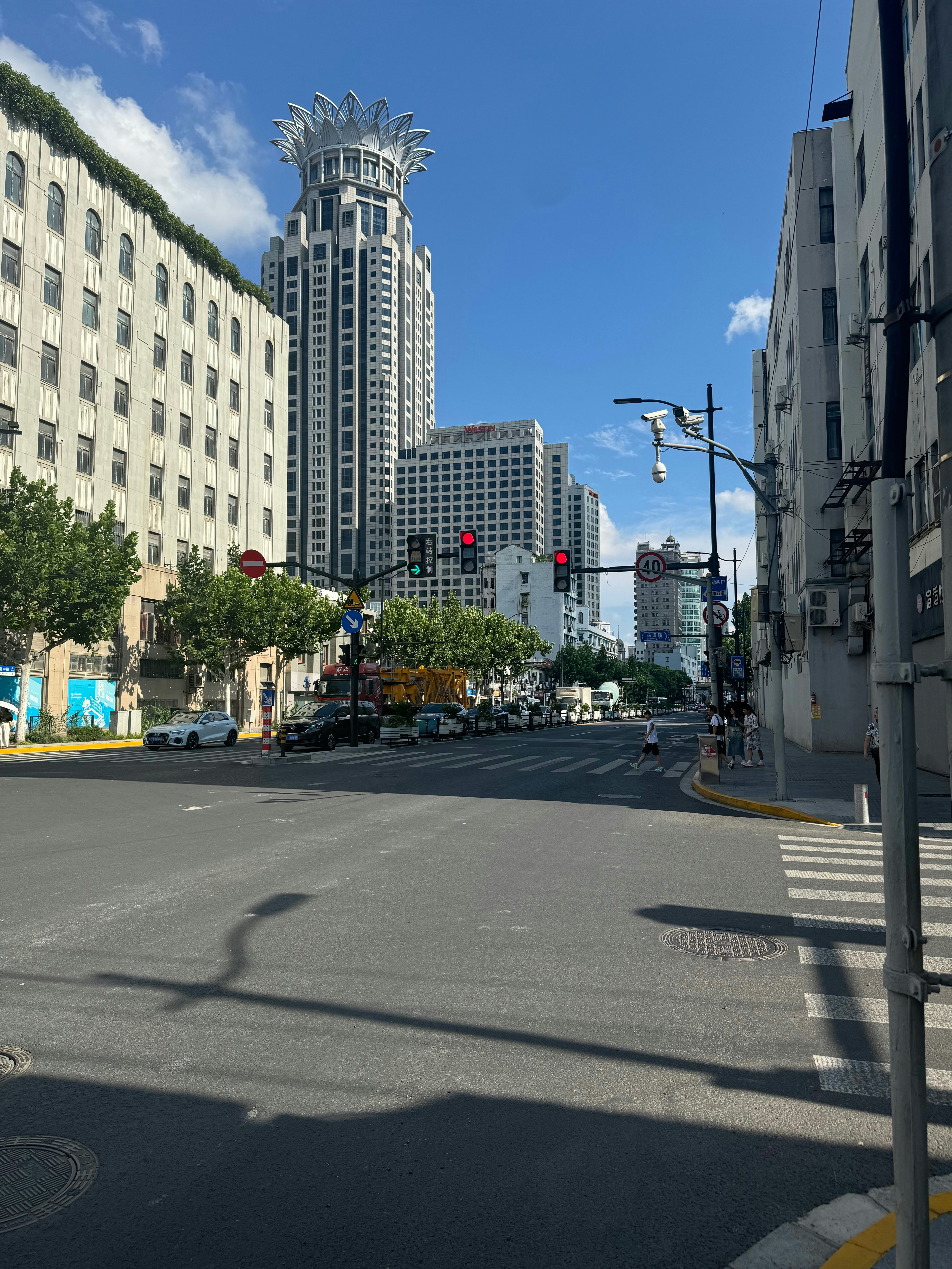 Busy city intersection with cars and pedestrians in clear daylight, open urban environment, bright natural lighting