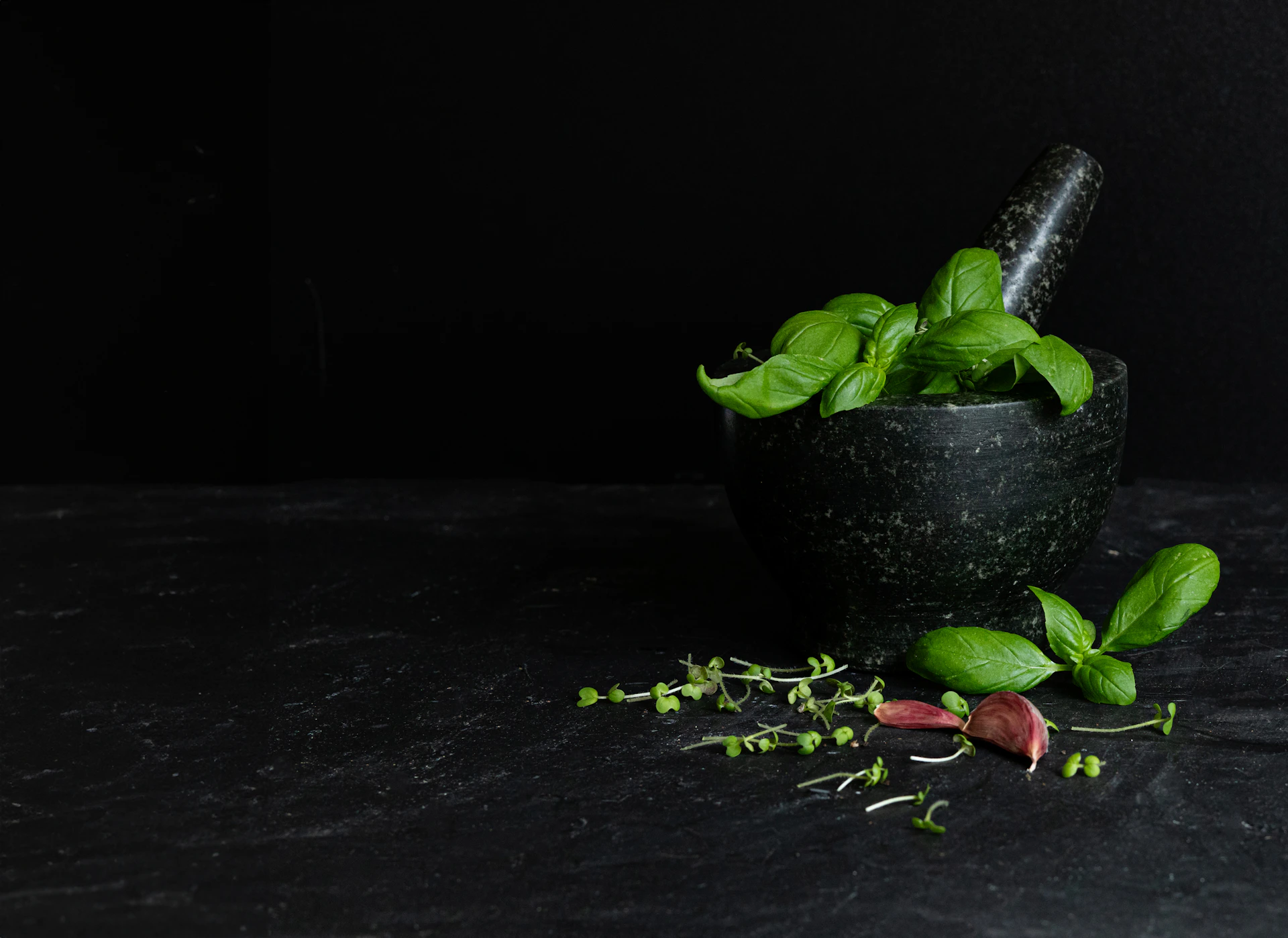 A mortar filled with green leaves on top of a table