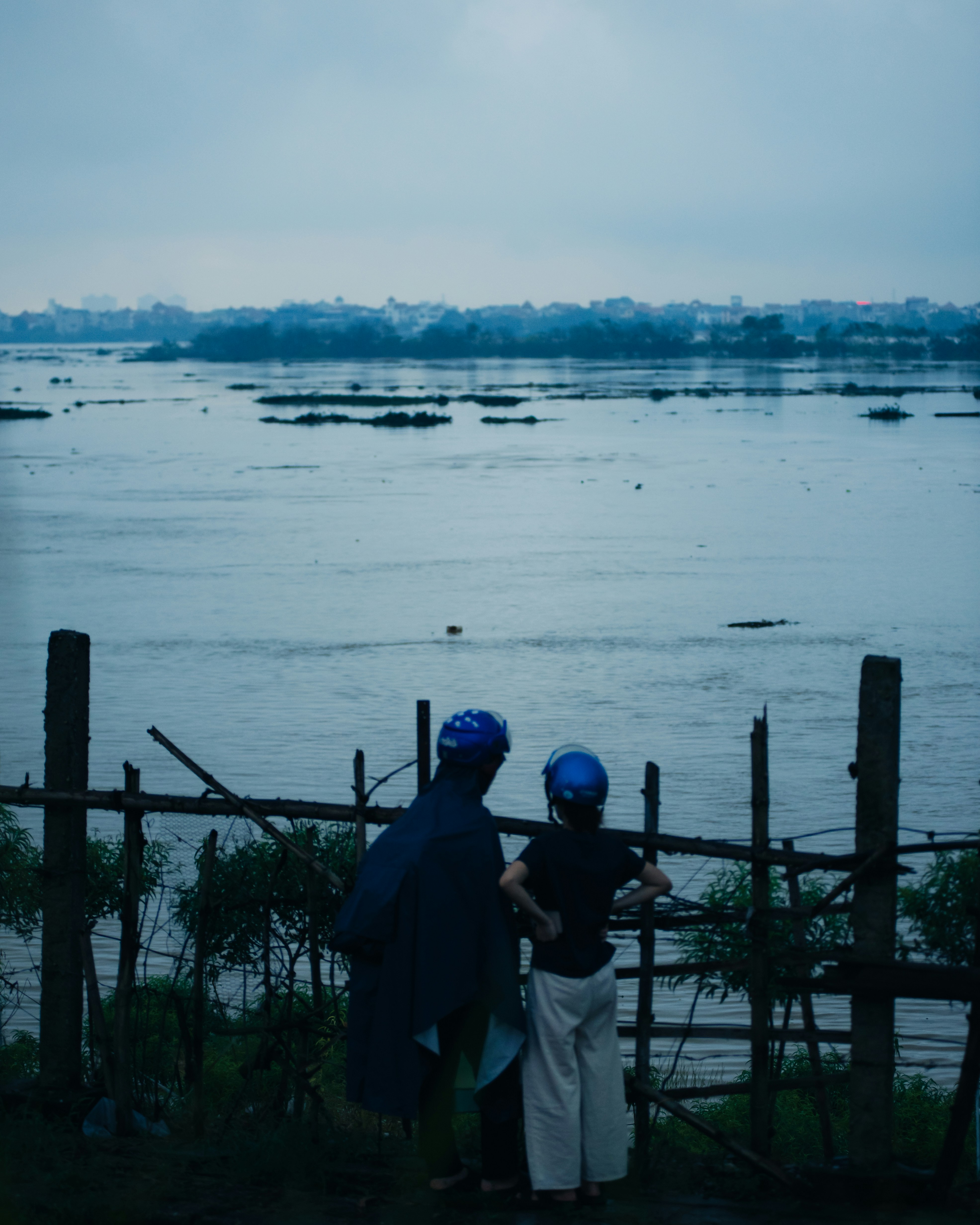 A couple of people standing next to a body of water