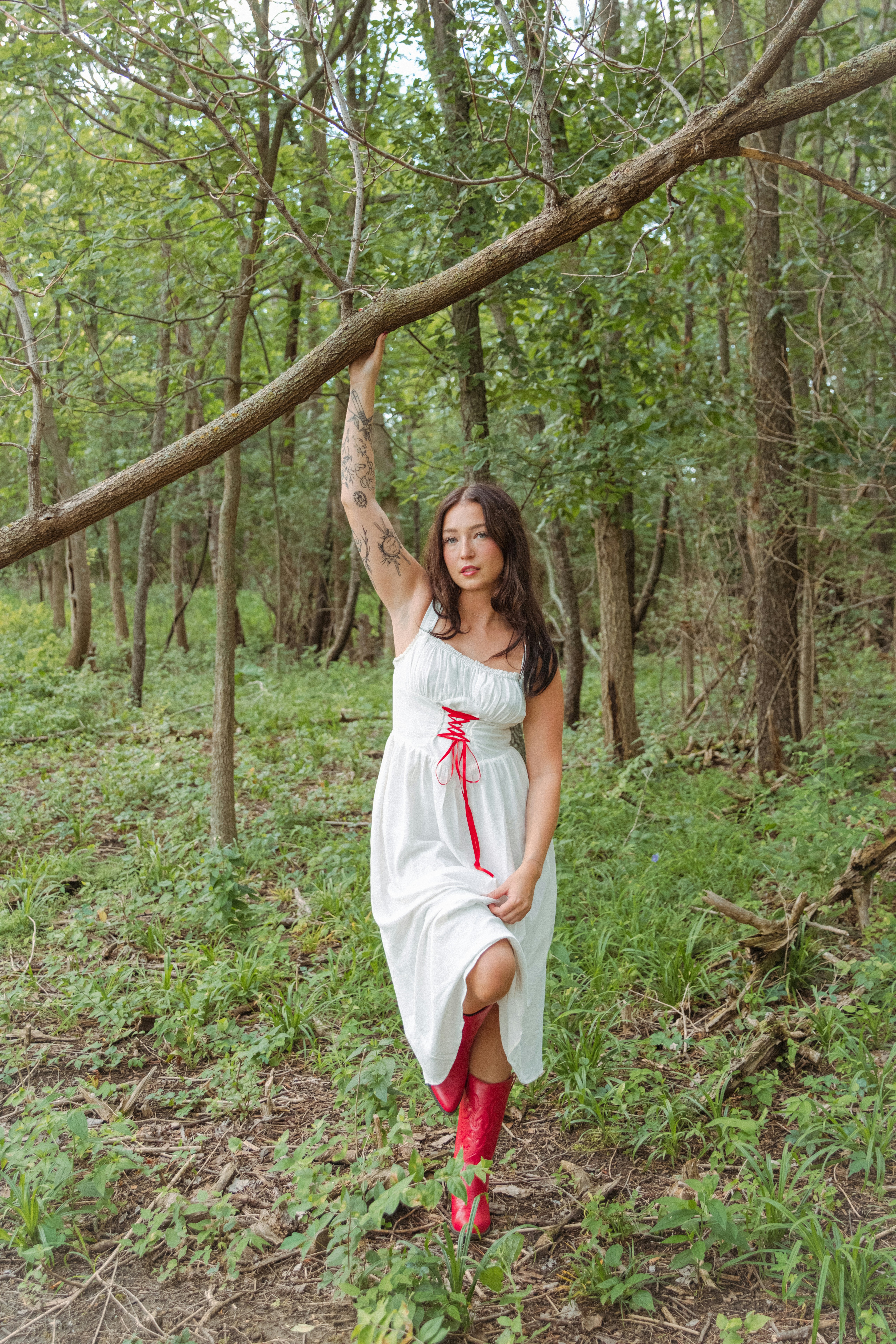 A woman in a white dress is standing in the woods