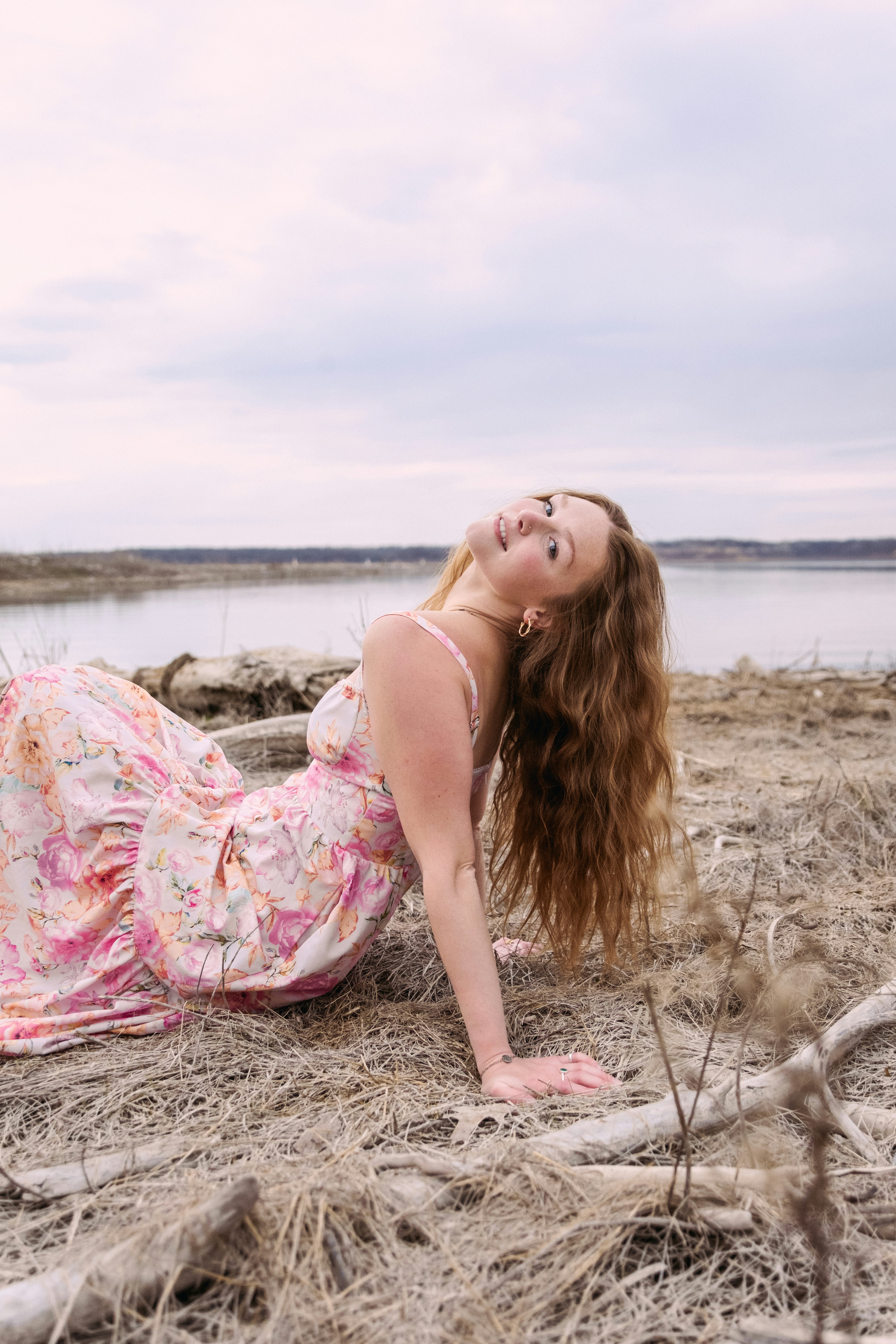A woman laying on the ground next to a body of water
