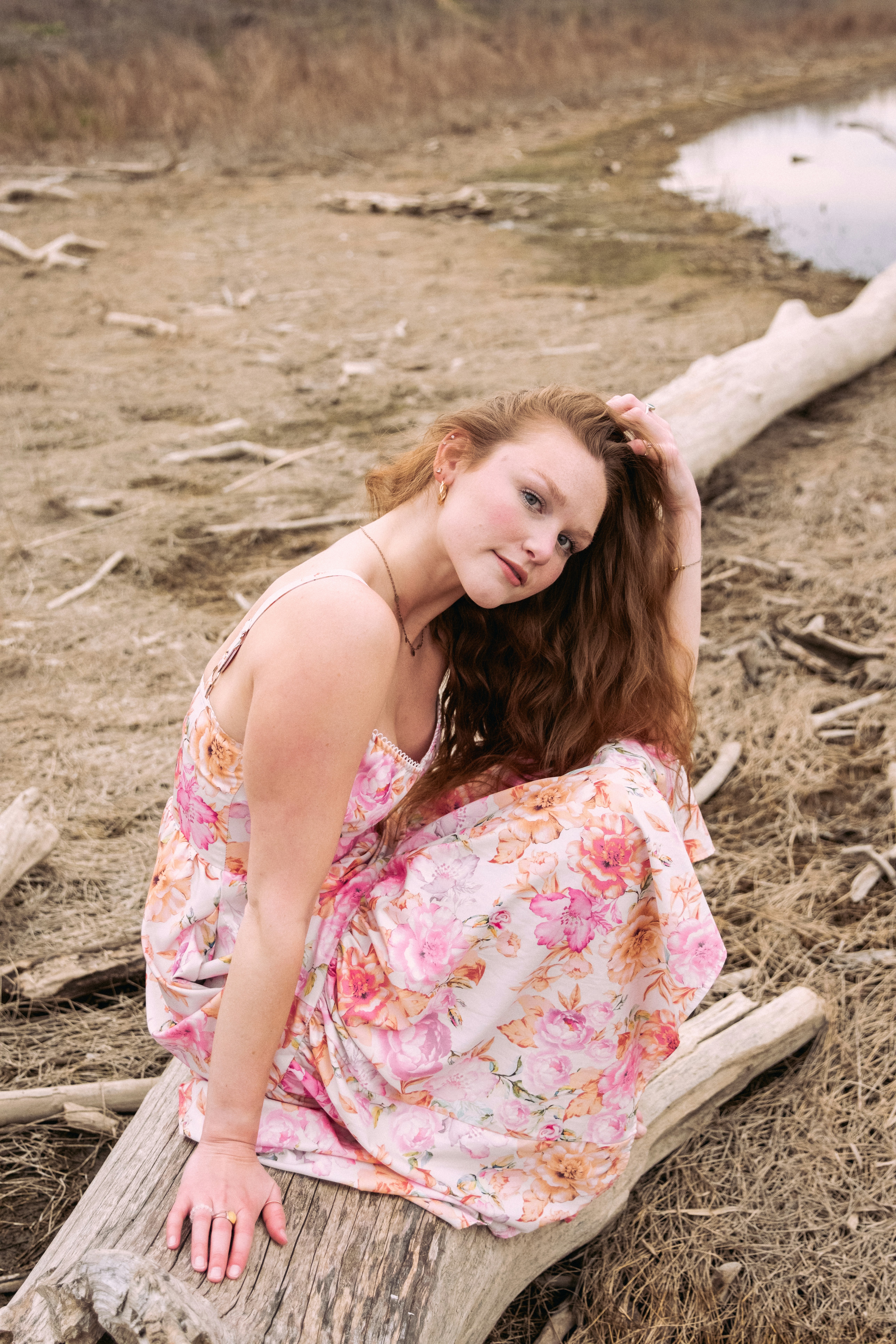 A woman sitting on a log in a field