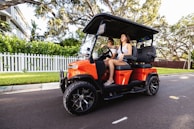 A woman driving a golf cart down a street