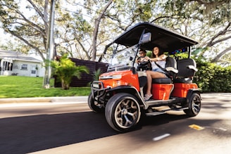 Two people riding in a golf cart on a street