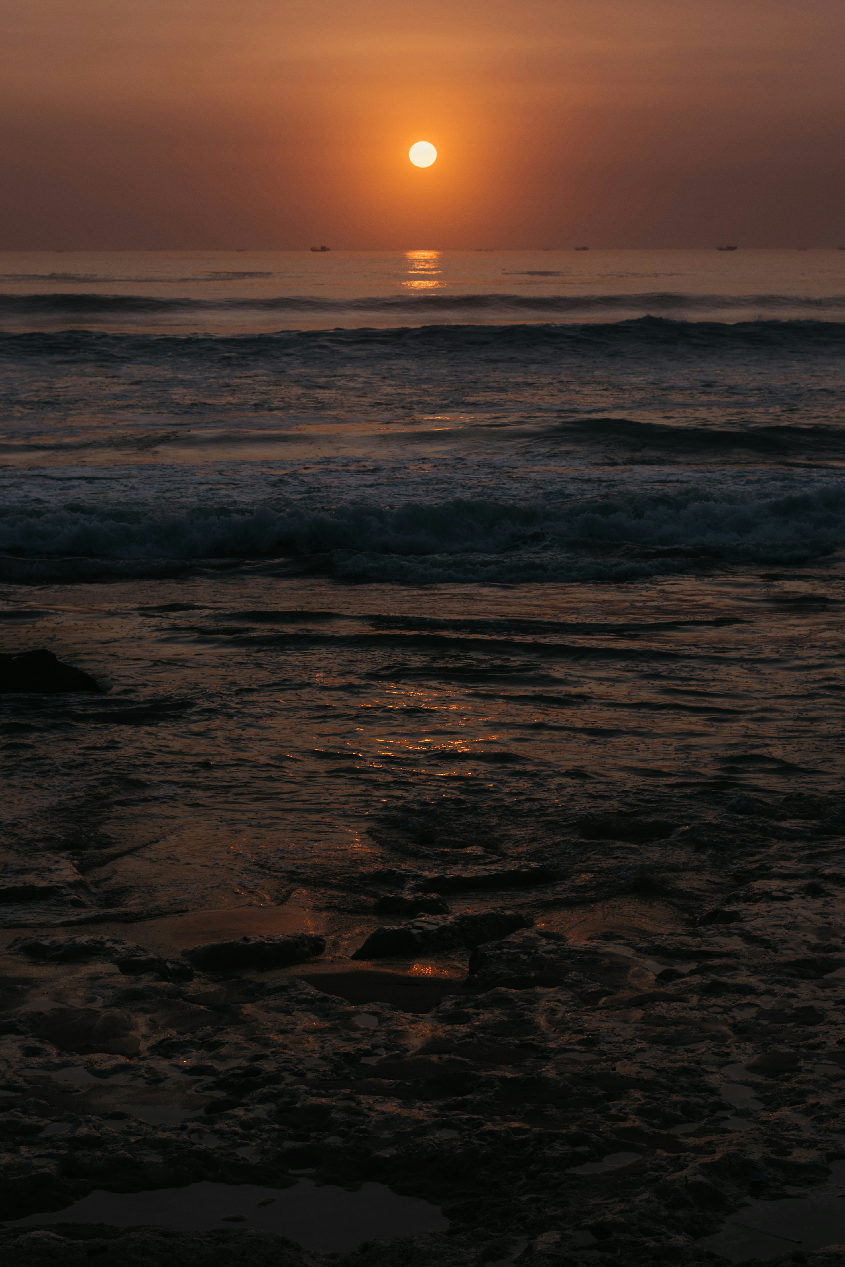 The sun is setting over the ocean on a cloudy day