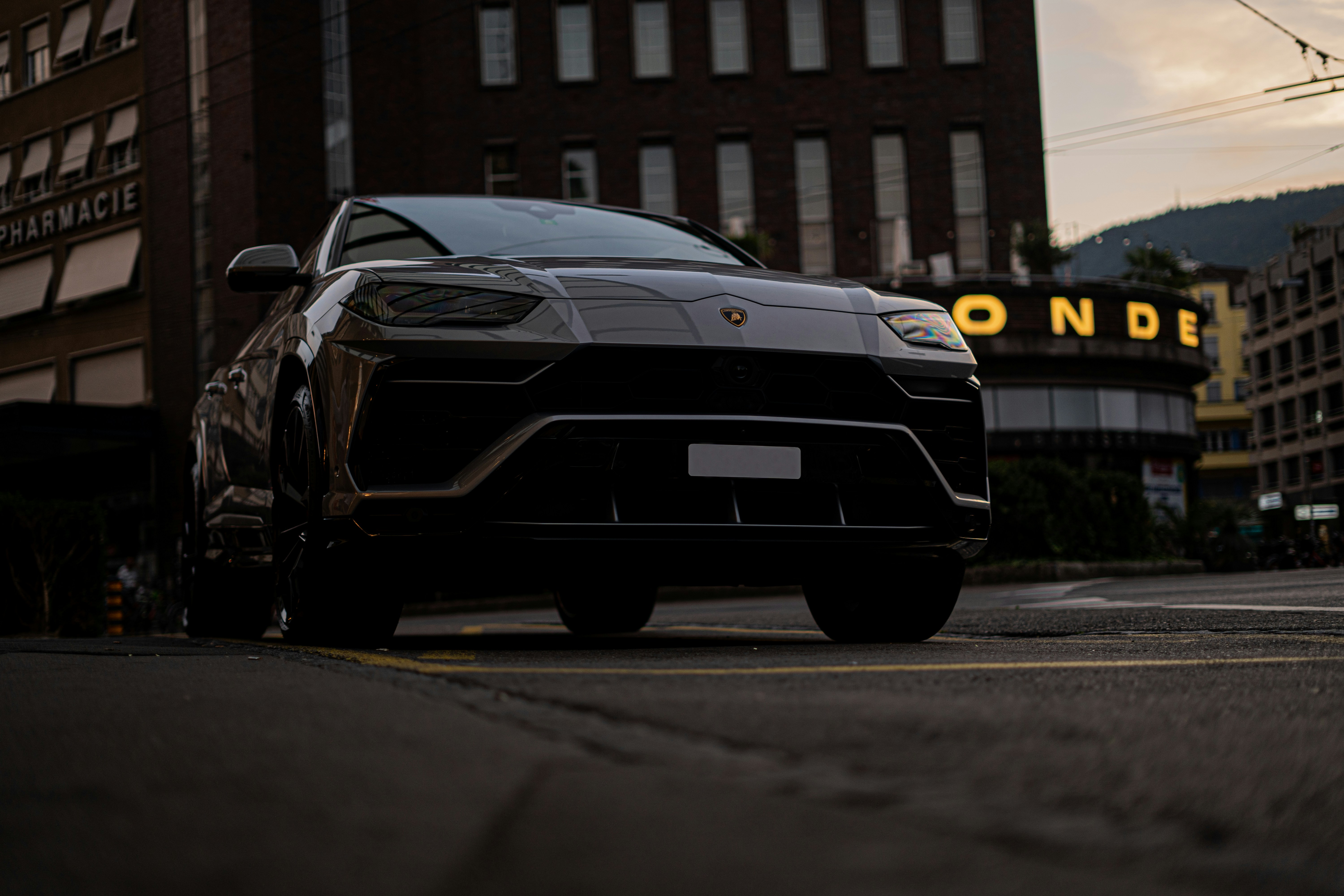 Dark grey midsize SUV parked in city, sleek modern styling, ambient evening light