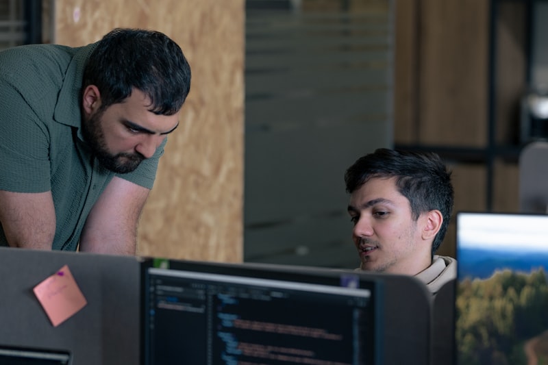 Two developers inspecting code together at a desk