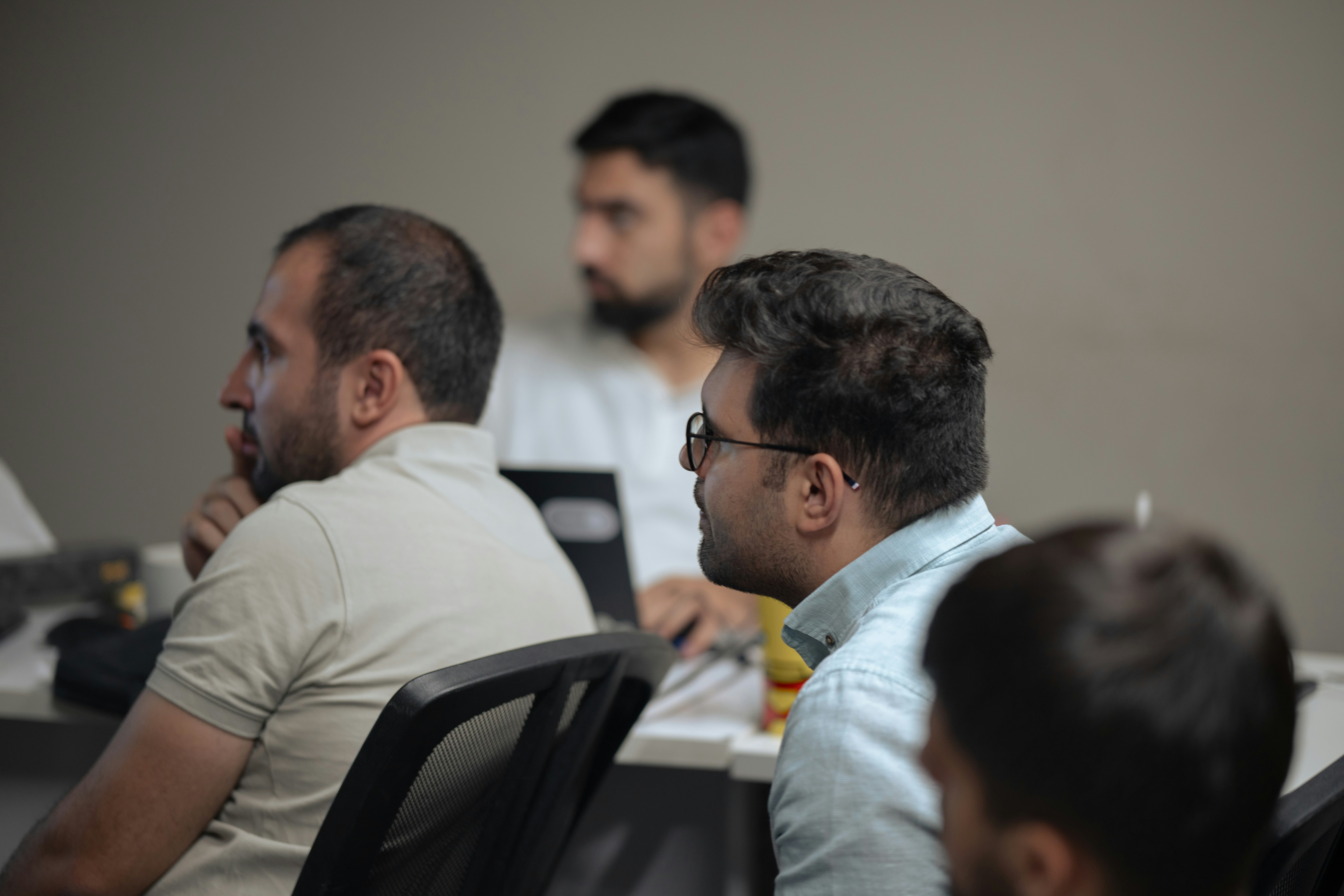 A group of men sitting at a table with laptops