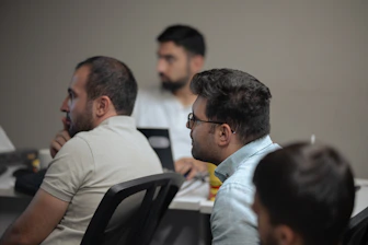A group of men sitting at a table with laptops