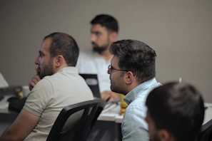 A group of men sitting at a table with laptops