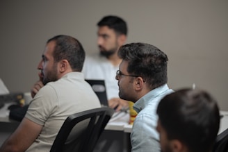 A group of men sitting at a table with laptops