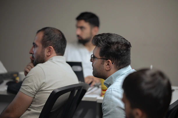 A group of men sitting at a table with laptops