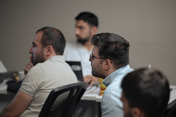 A group of men sitting at a table with laptops