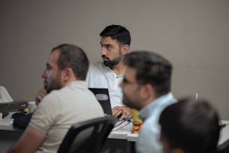 A group of men sitting at a table with laptops