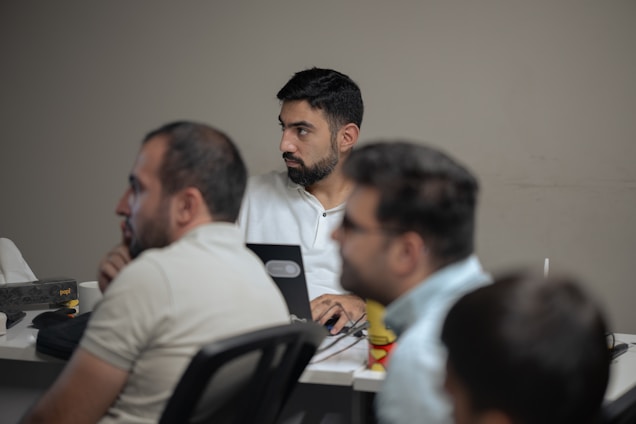 A group of men sitting at a table with laptops