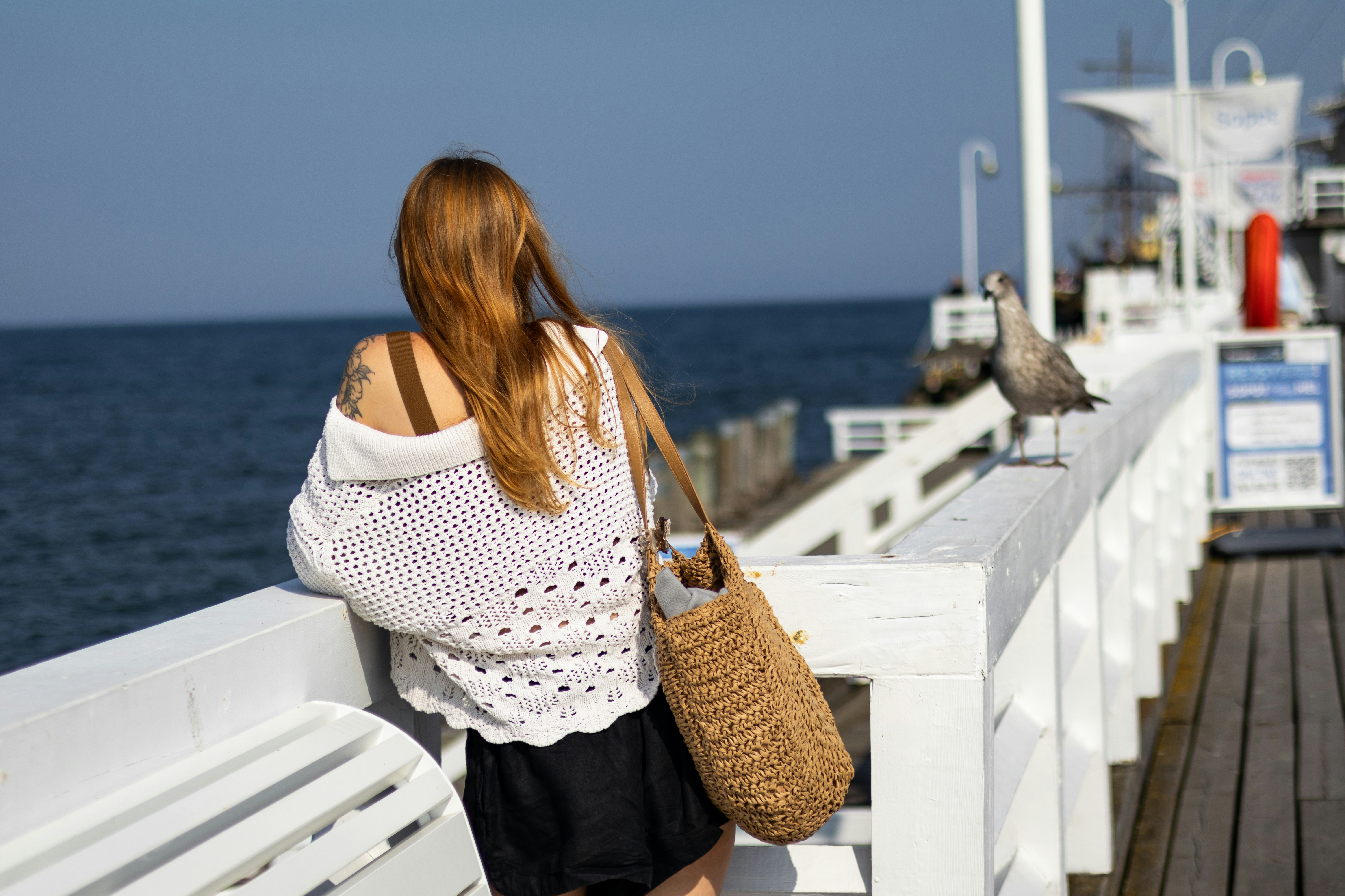 A woman sitting on a bench looking out at the ocean