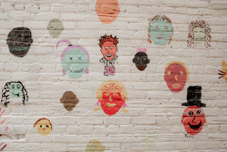 A white brick wall with a bunch of different faces on it