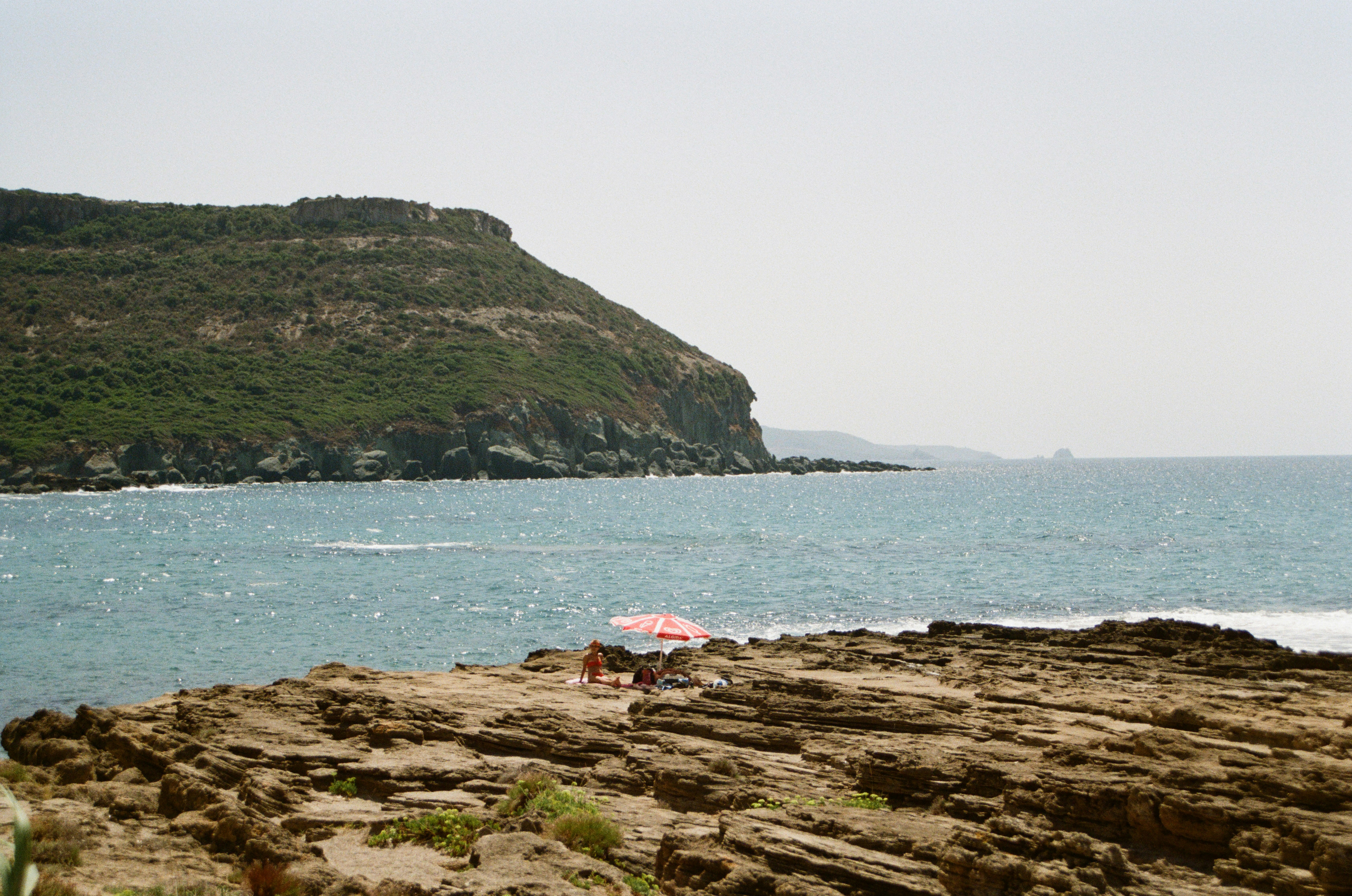 A person standing on a rocky beach next to the ocean
