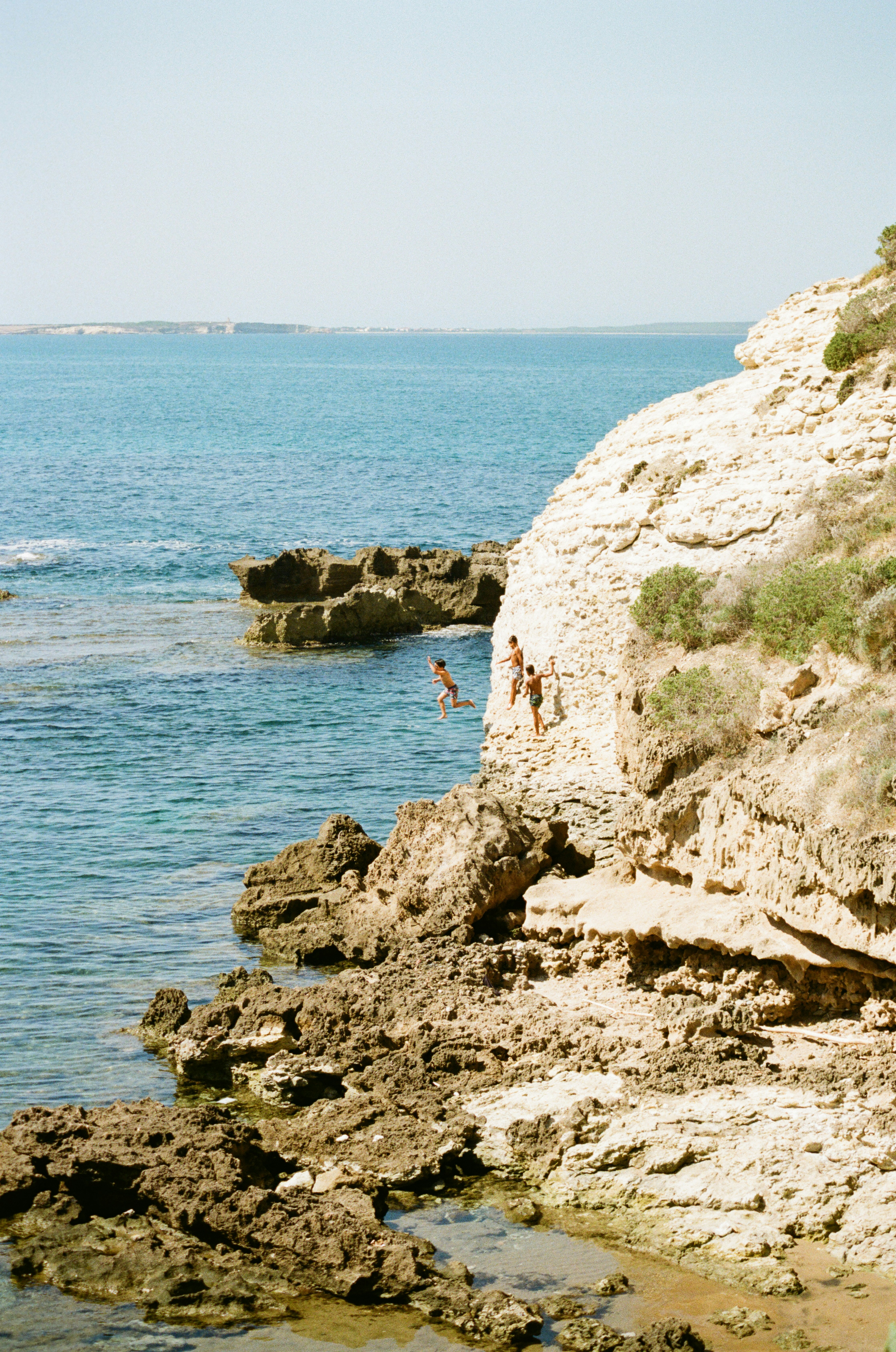 A man standing on top of a cliff next to the ocean