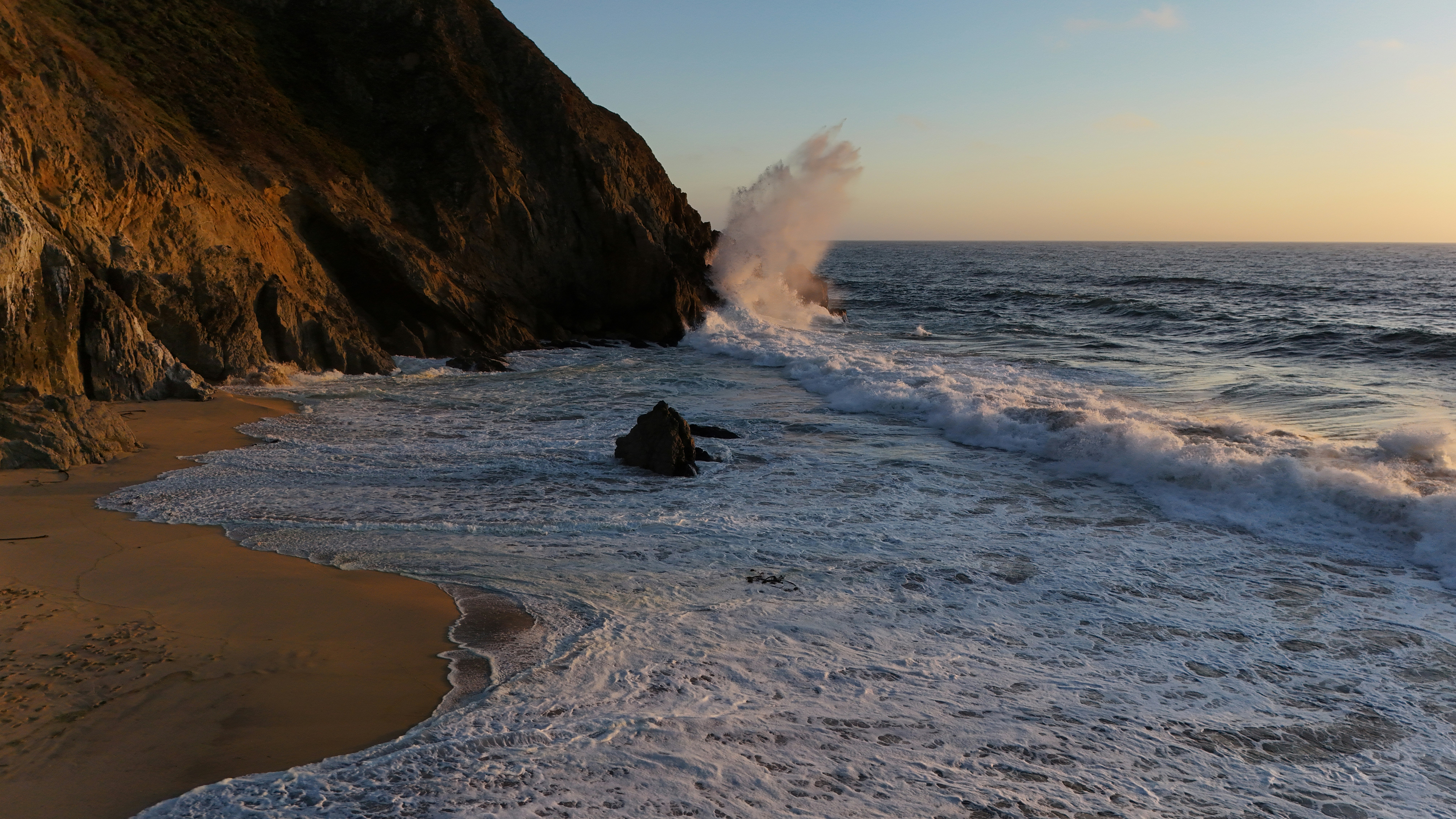 A wave crashes into the shore of a beach