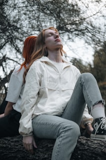A woman with red hair sitting on a tree branch