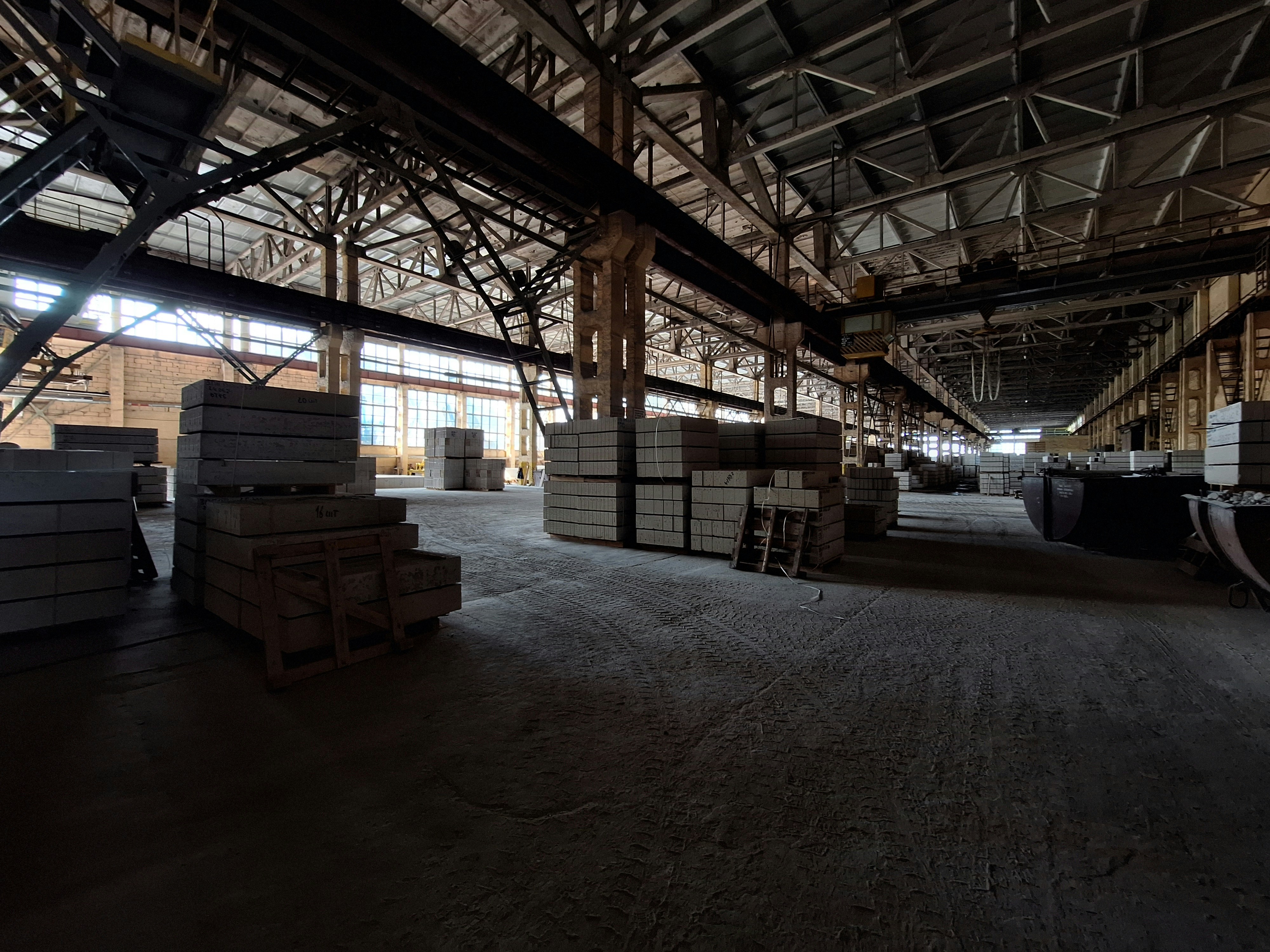 Cement warehouse interior with stacked bags in dim industrial lighting, concrete walls, low-key storage facility atmosphere