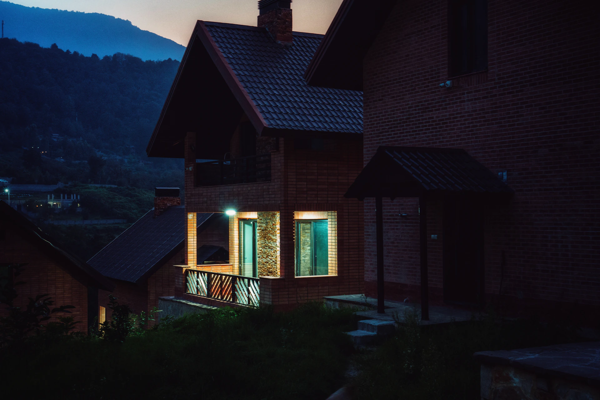A house is lit up at night with mountains in the background