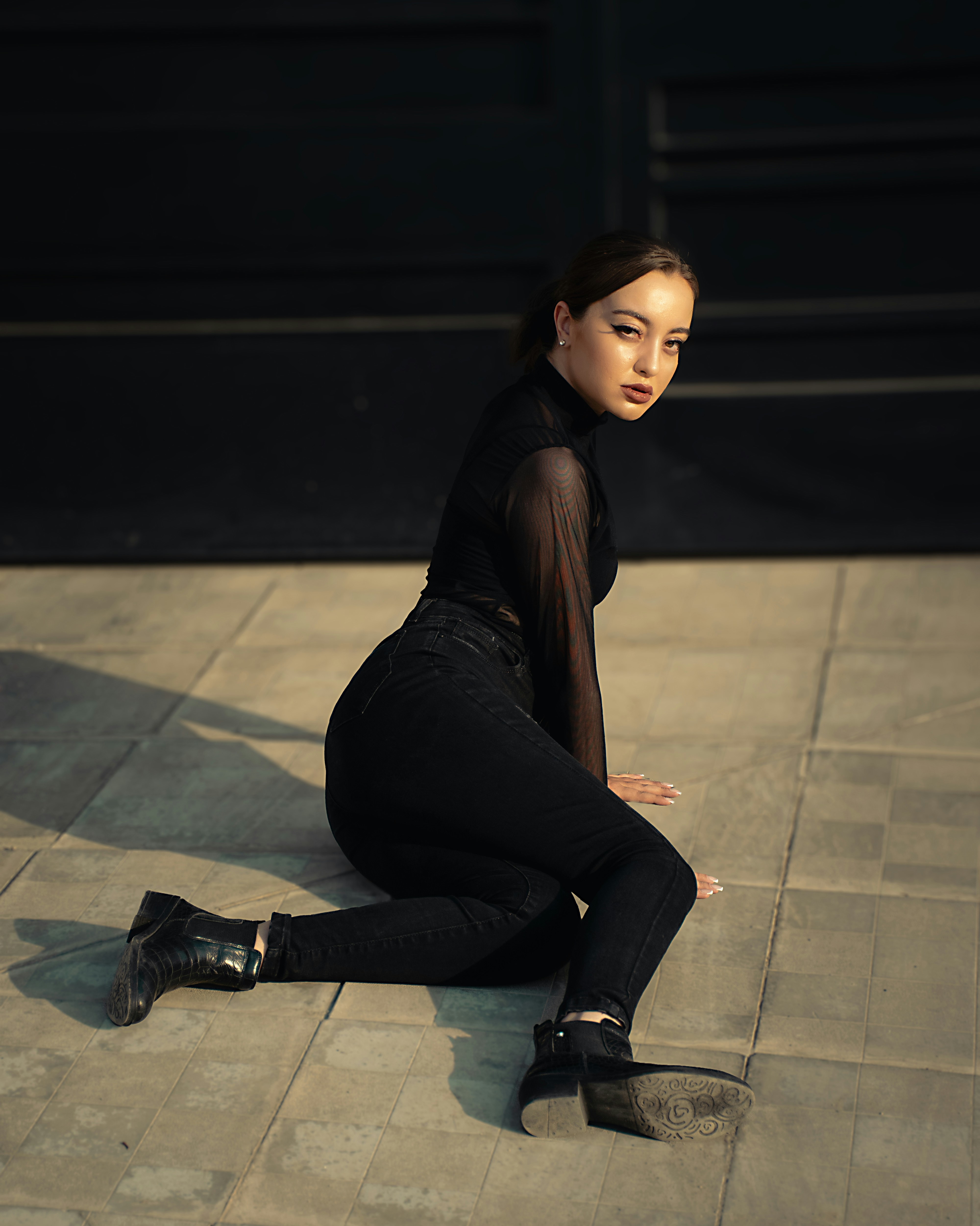 A woman sitting on the ground in a black outfit photo – Free Woman ...