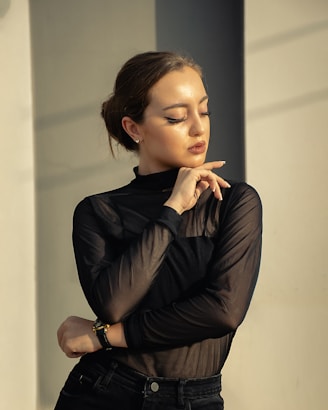 A woman in black shirt and jeans leaning against a wall
