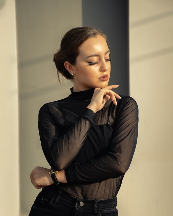 A woman in black shirt and jeans leaning against a wall