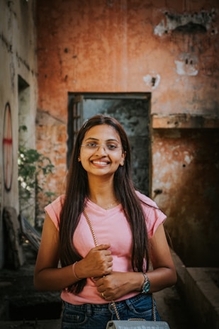 A woman standing in an alleyway holding a purse