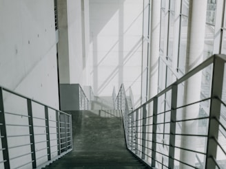 A long hallway with metal railings leading up to a building