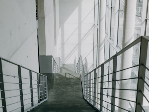A long hallway with metal railings leading up to a building