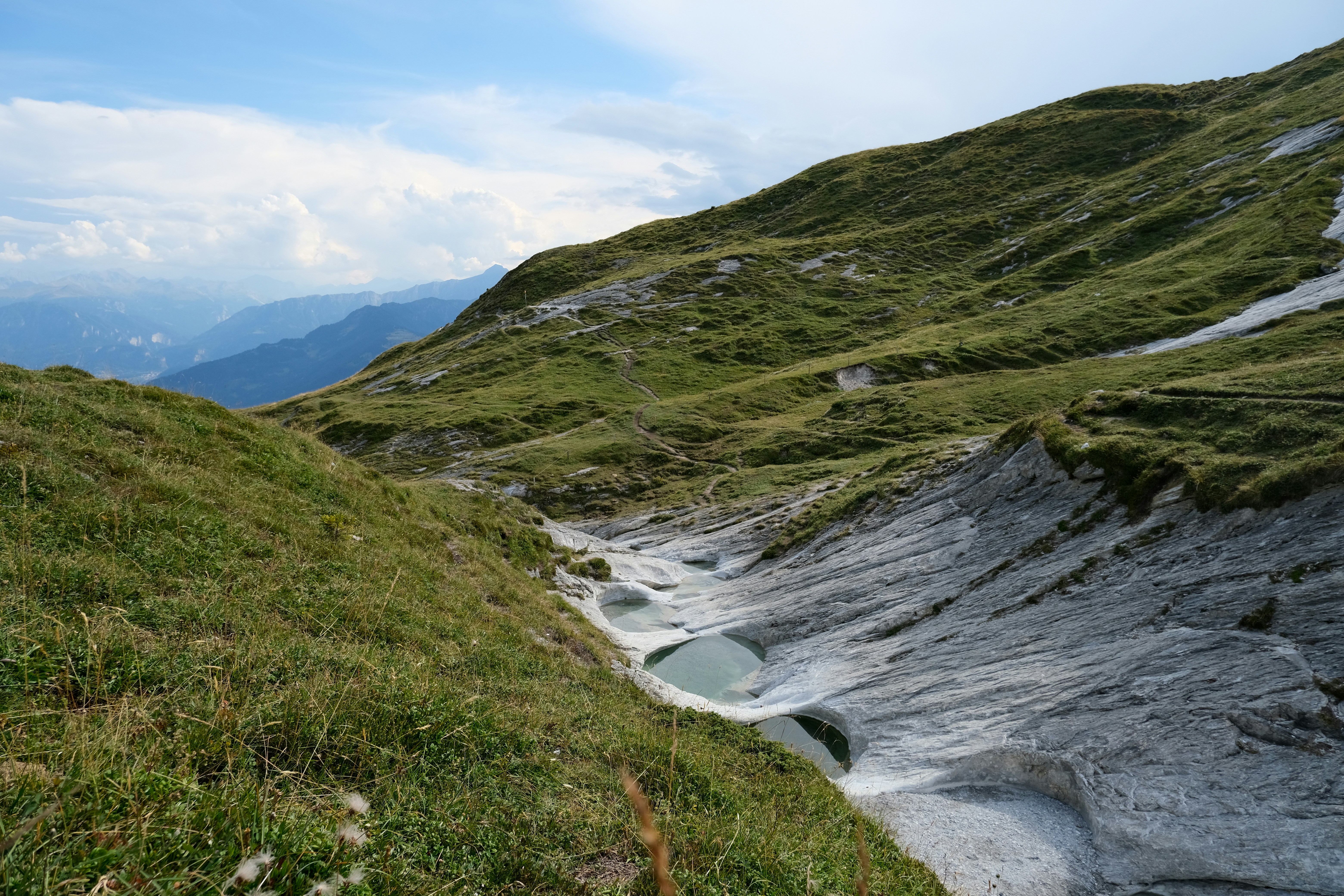 Una colina cubierta de hierba con un pequeño arroyo que la atraviesa
