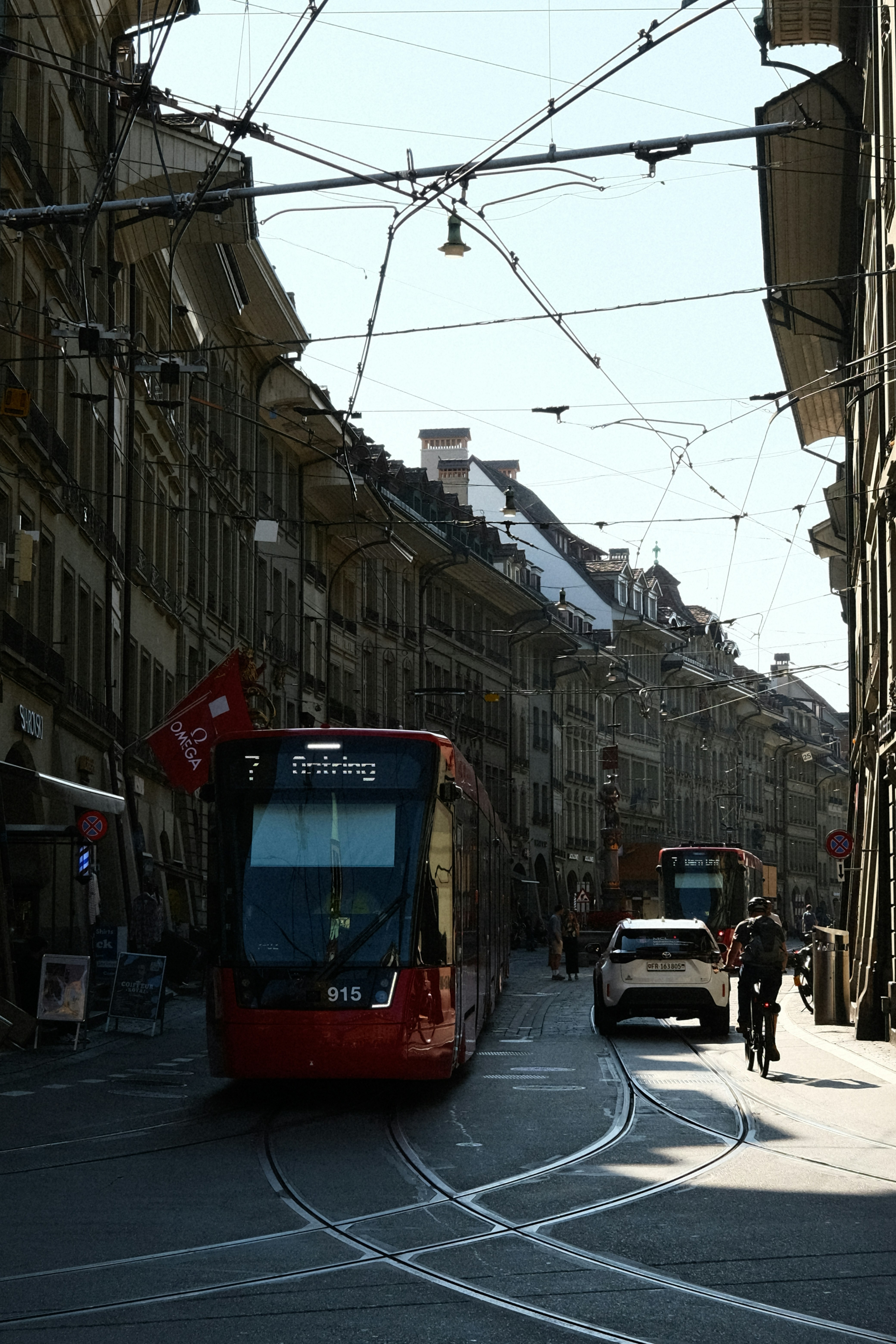 Un autobús rojo circulando por una calle junto a edificios altos