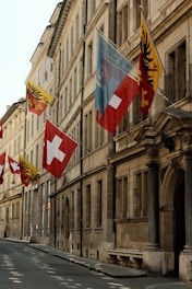 A row of flags on a street next to a building