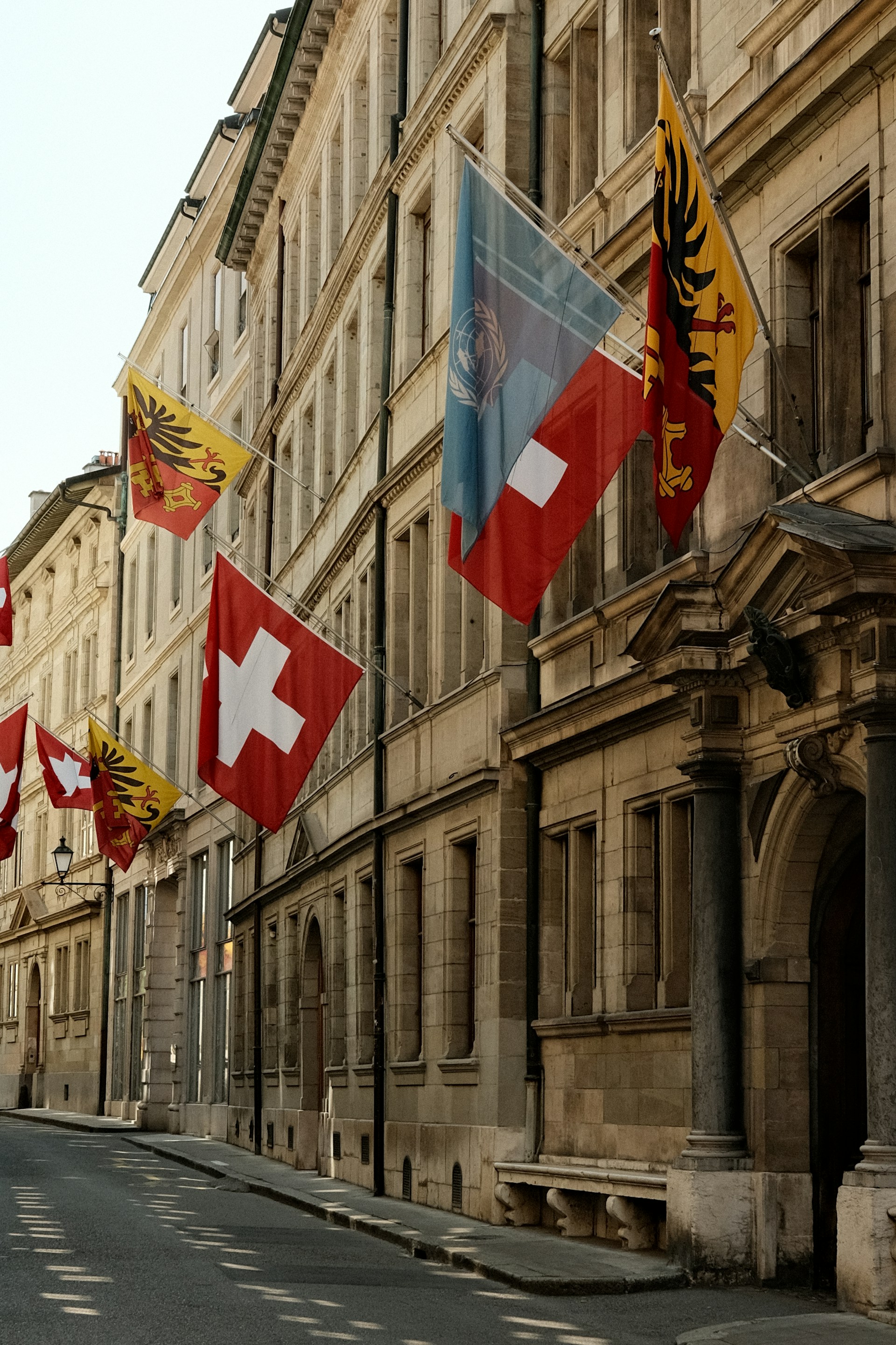 A row of flags on a street next to a building