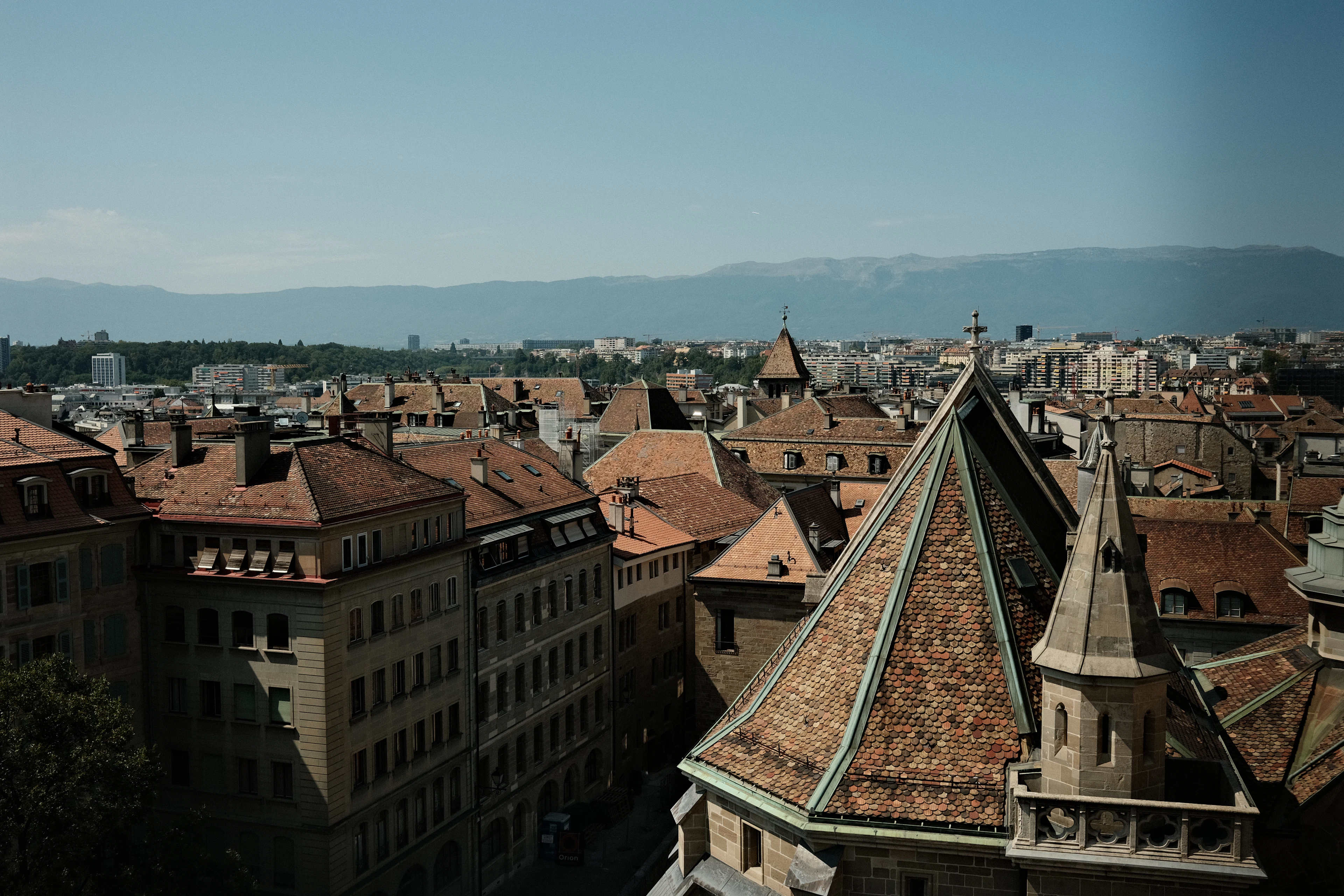Terracotta rooftops and a church spire seen from above in Geneva's old town.