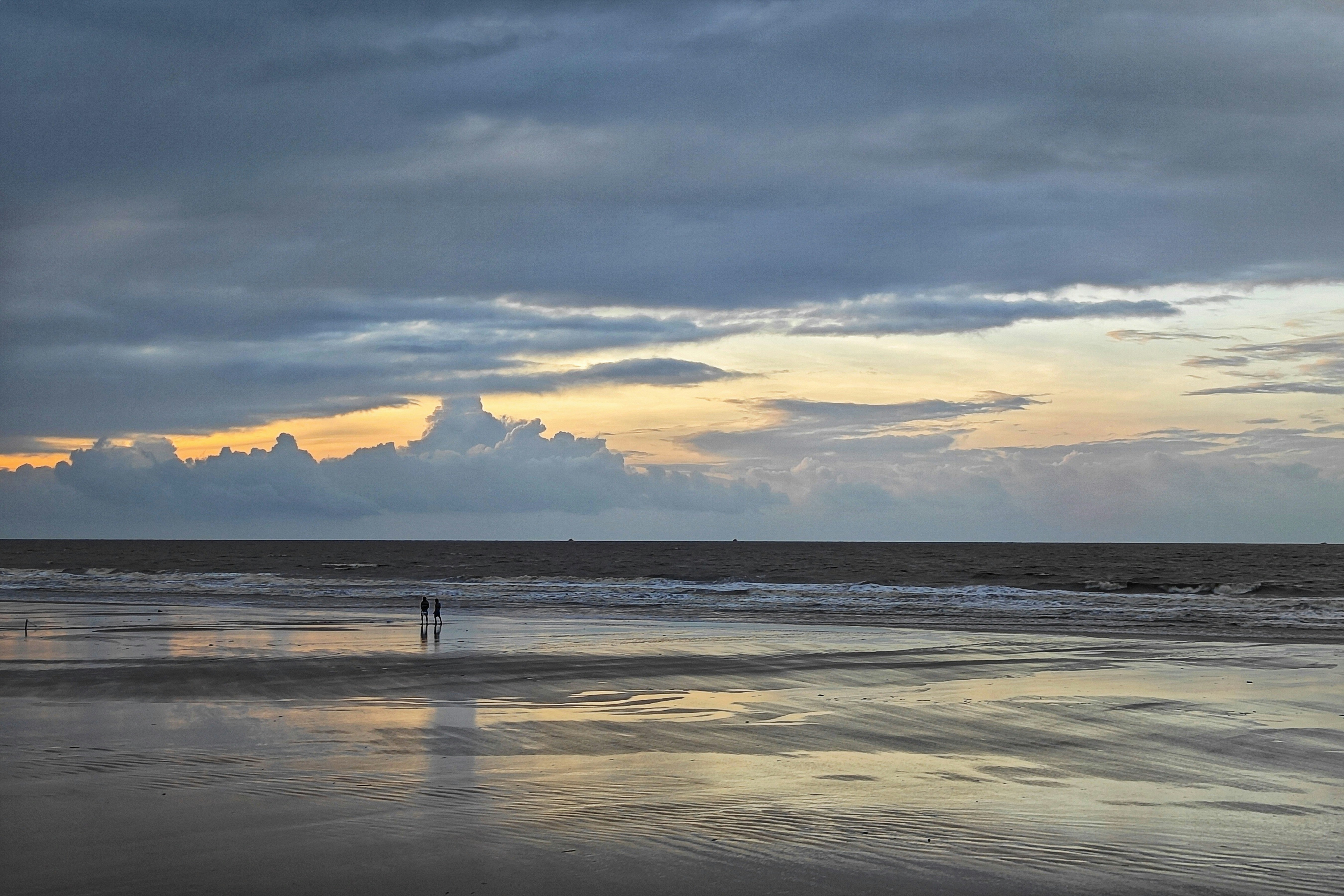 A person walking on the beach at sunset