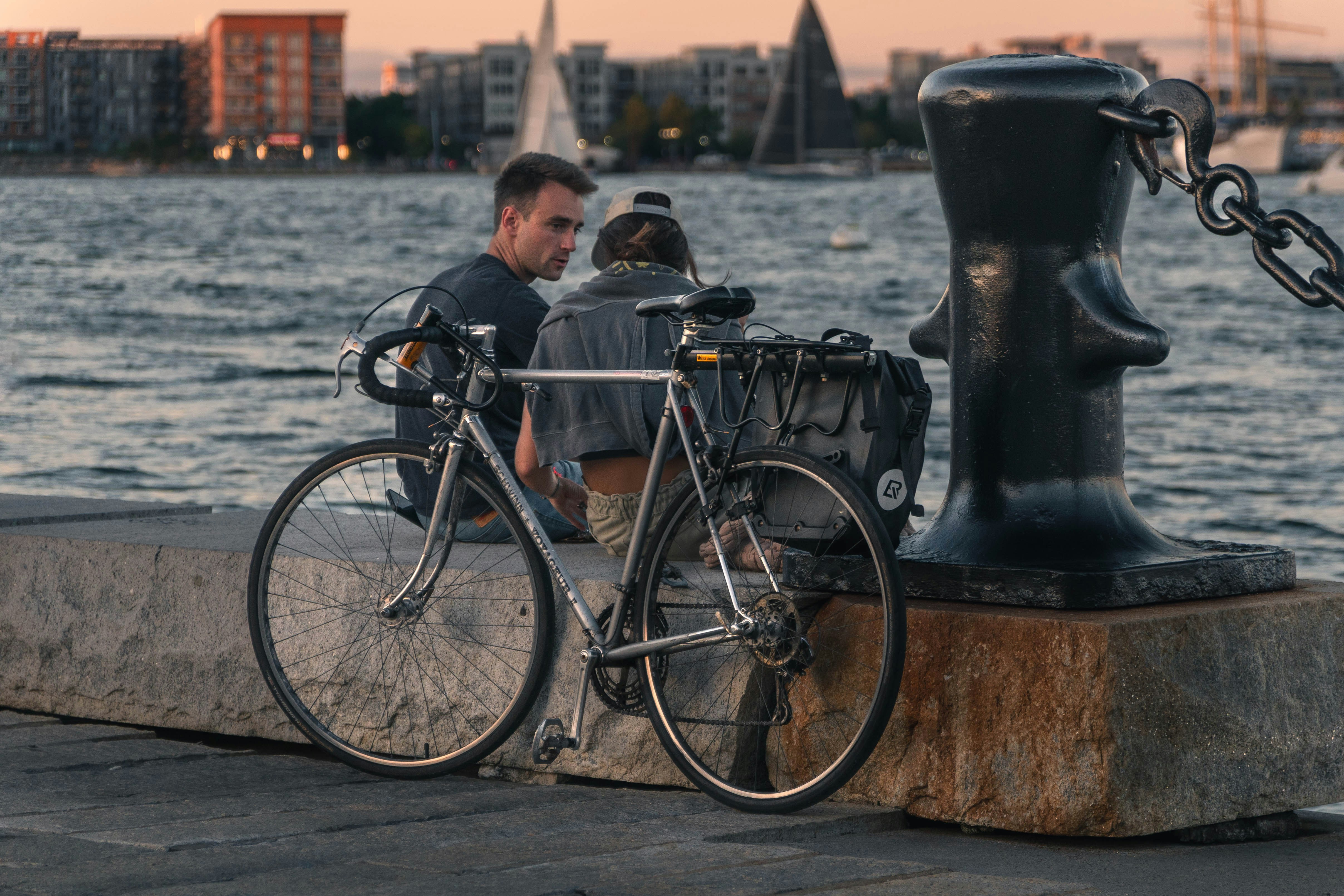 A couple of people sitting next to a bike near a body of water