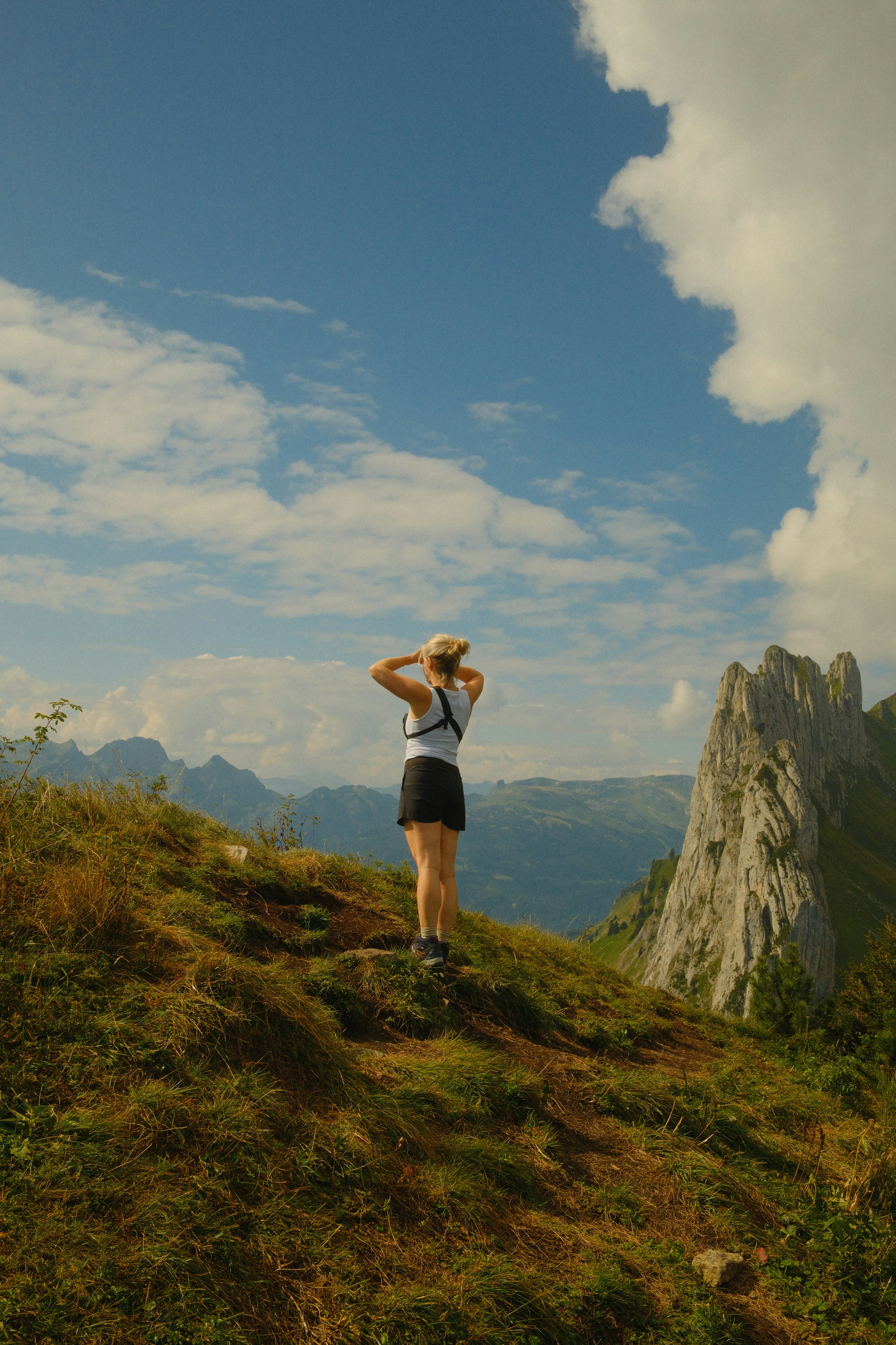 Una mujer de pie en la cima de una exuberante ladera verde
