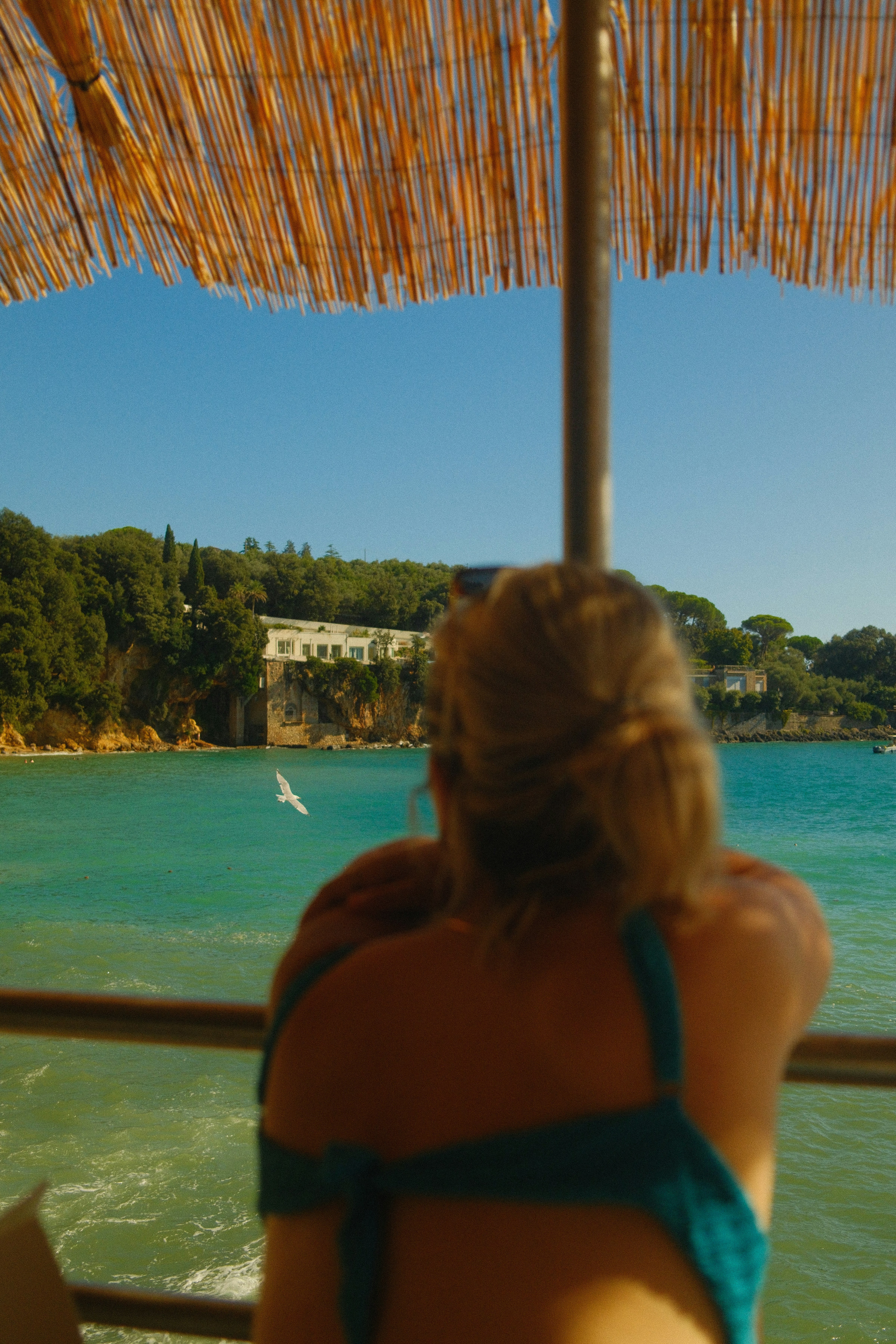Una mujer en bikini sentada bajo un paraguas