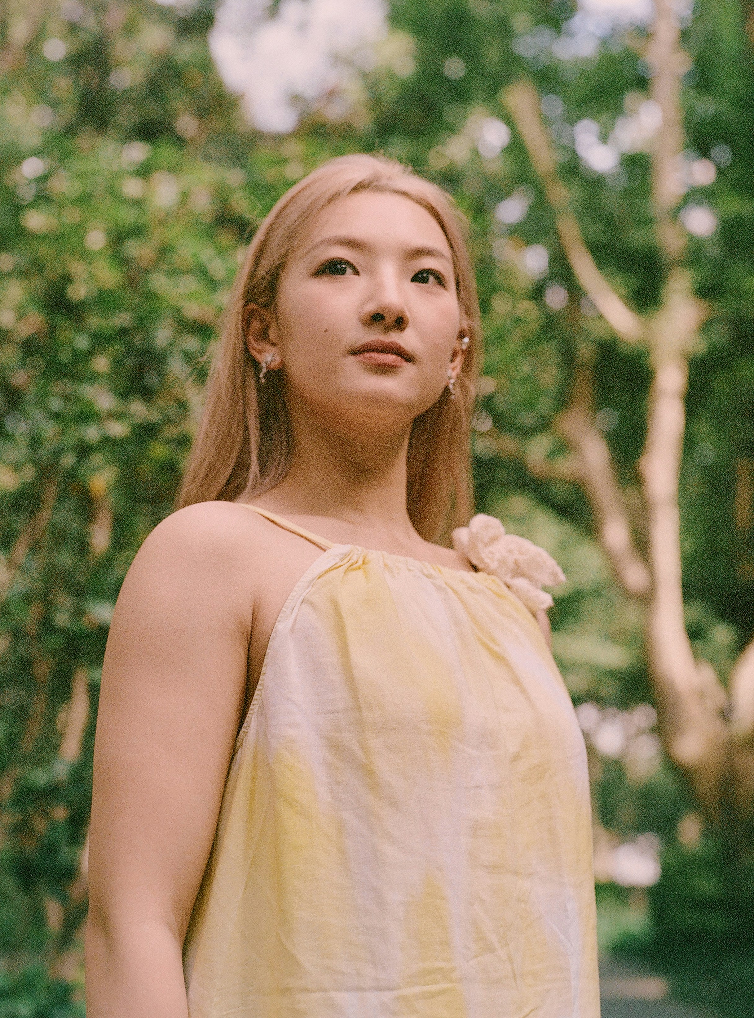 A woman in a yellow dress standing in a park